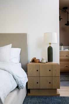 a bedroom with a bed, dresser and lamp