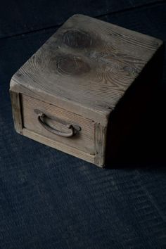 a wooden box sitting on top of a blue floor next to a black wall with a metal handle