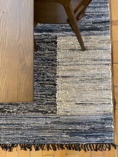 a chair and rug on the floor in front of a wooden table with two chairs