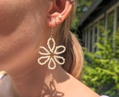 These unique daisy drop and dangle earrings are the perfect accessory for parties and formal events. Perfect for weddings and bridal events. Earrings are made with 2mm ivory white glass beads and 2mm gold glass beads on 28g gold colored copper wire.  Available in 6 petal style and 8 petal style.   Jewelry Care: *Avoid getting jewelry wet is possible to ensure the jewelry lasts as long as possible. *Color and length may vary very slightly as these earrings are handmade* Elegant White Flower Shaped Beaded Earrings, Gold Flower-shaped Beaded Earrings, Elegant Gold Flower Beaded Earrings, Elegant Gold Flower-shaped Beaded Earrings, Spring White Pearl Earrings, White Pearl Earrings With Gold Beads, Bridal Events, Grand Haven, Bridal Event