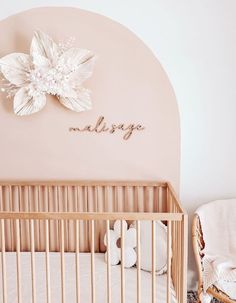 a baby's room with a crib, rocking chair and large flower on the wall