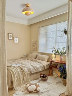 a bed sitting under a window next to a table with a stuffed animal on it