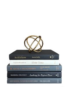 three books stacked on top of each other in front of a white background with a gold ring