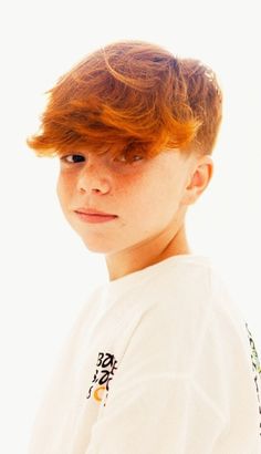 a young boy with red hair wearing a white shirt