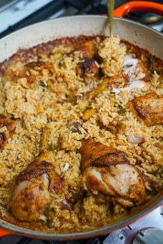 a pan filled with rice and chicken sitting on top of an orange stove burner