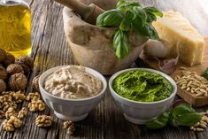 several different types of food on a wooden table with nuts, cheese and pesto