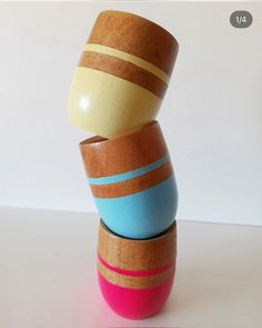 three wooden bowls stacked on top of each other in different colors and sizes, one is blue, the other has pink