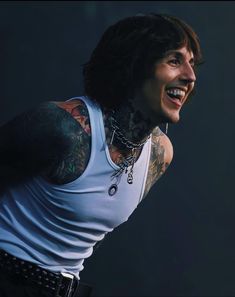 a man with tattoos and piercings on his arm, standing in front of a dark background