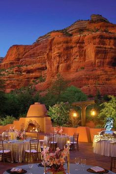 an outdoor dining area with tables and chairs in front of a mountain range at night