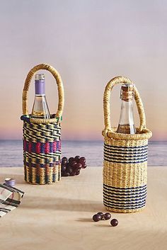 two wicker baskets with wine bottles in them on a table next to the ocean