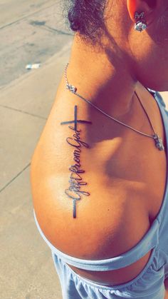 a woman with a cross tattoo on her upper back shoulder and the word faith written in cursive writing