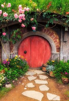 a red door surrounded by flowers and greenery