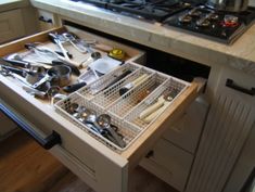 an open drawer in a kitchen with utensils and other items on the counter