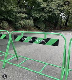 a green metal gate with two black and white signs that say bottega veneta