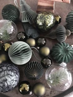 some glass ornaments are sitting on a table together, and one is black with gold accents