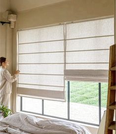 a person standing next to a window in a bedroom