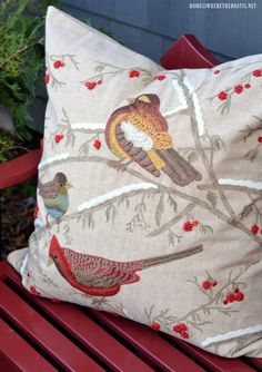 a pillow with birds on it sitting on a red bench