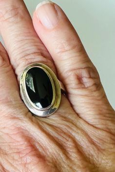 Crafted in the style of vintage jewelry from the 1980s, this sterling silver onyx ring embodies a timeless charm that is both minimalist and elegantly understated. The bezel-set oval black onyx stone, measuring approximately 17mm by 10mm, radiates sophistication and allure. With a delicate size 6 fitting, this ring is the perfect gift for your girlfriend's birthday, anniversary, Christmas, Hanukkah, or Valentine's Day.  For the woman who adores silver jewelry, this piece is a lovely everyday ring that seamlessly transitions from casual to formal occasions. Whether it's a treat for yourself or a heartfelt gesture for a loved one, this bold statement ring speaks volumes of style and grace. Stamped with "Thailand" and "NF 925" on the inside of the band, this ring is a symbol of quality crafts Timeless Oval Black Enamel Jewelry, Modernist Oval Jewelry For Formal Occasions, Minimalist Oval Onyx Jewelry, Modern Black Oval Jewelry, Classic Black Enamel Oval Ring, Classic Oval Black Enamel Ring, Black Oval Jewelry With Bezel Setting, Polished Oval Onyx Jewelry, Classic Black Oval Cabochon Ring