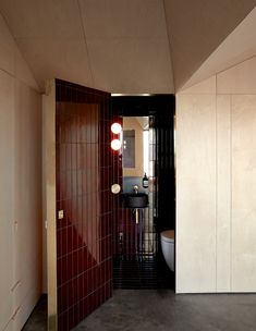 an open door leading to a bathroom with red tiles on the walls and flooring