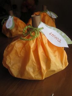 two orange pumpkins sitting on top of a wooden table with name tags attached to them