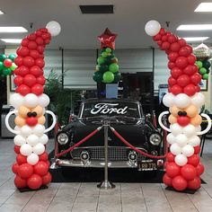 an old car decorated with balloons in the shape of santa clause