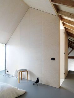 a bedroom with white walls and flooring next to a wooden ceiling mounted on the side of a wall