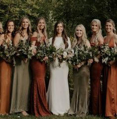 a group of women standing next to each other wearing dresses and holding bouquets in their hands