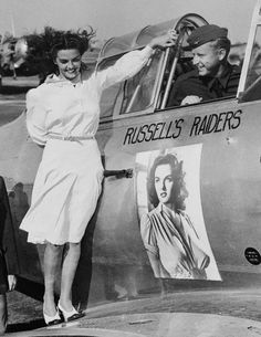 an old black and white photo of two women standing next to a plane