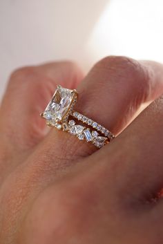 a close up of a person's hand holding an engagement ring with two diamonds on it