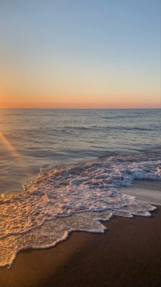 the sun is setting over the water at the beach