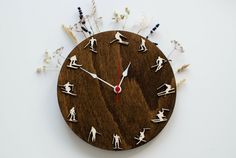 a clock made out of wood with white flowers and people on the face is shown