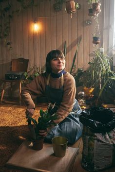 a woman sitting on the floor with potted plants