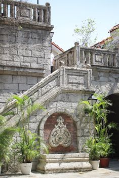 an old stone building with plants and potted plants on the steps to the entrance