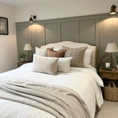 a bed with white sheets and pillows in a bedroom next to two lamps on either side of the bed