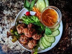 a white plate topped with meatballs and veggies next to a cup of tea