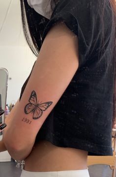 a woman with a butterfly tattoo on her right arm and left arm behind her back