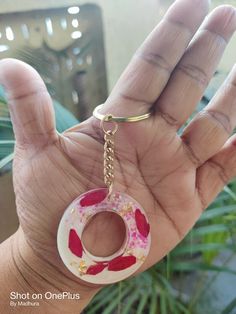 a hand holding a pink and white doughnut with sprinkles on it