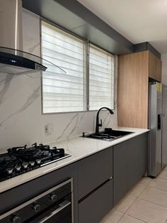 a kitchen with marble counter tops and stainless steel appliances, along with white tile flooring