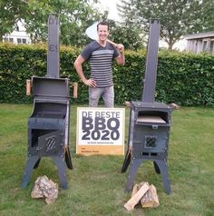 a man standing next to two charcoal smoker ovens in the grass with a sign that says de beste bbq 2020