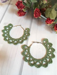 green crochet hoop earrings on white wood with red roses in the back ground