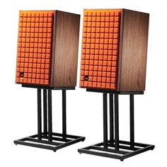 two speakers are sitting side by side on black metal stands, one is orange and the other is brown