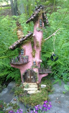 a pink fairy house sitting on top of a rock