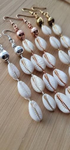 several different types of seashell earrings on a wooden table with gold and silver earwires