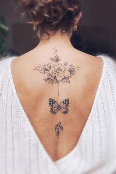 the back of a woman's neck with a butterfly and flowers tattoo on it