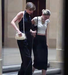 two women in black and white outfits walking down stairs