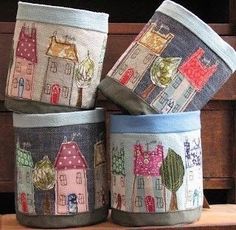 four pots with houses on them sitting on a table