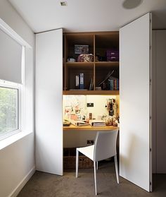 a white chair sitting in front of a desk under a book shelf next to a window