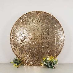 a large gold sequin covered plate sitting on top of a white table next to flowers