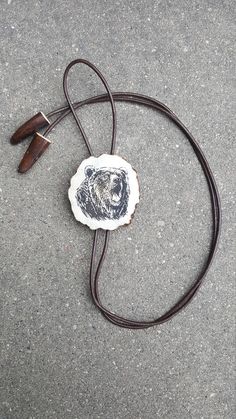 "Handmade bolo tie with engraved BEAR. Unique necklace with statement pendant from deer horn and long leather strip. Original gift for men. 100 % handmade. Great present for hunting, nature, wild animals, Western style lovers. ITEM DETAILS: * Horn thickness is ~ 1/4\" (6-7 mm), * Bolo tie diameter is ~ 2\" (5 cm). * Calibrated leather strap is 1/16\" (2 mm) thick, the ends are decorated with deer horn tips. Horn size, color and shape of this product can be different. ATTENTION FREE OPTIONS ----- Western Lariat Jewelry As Gift, Western Style Lariat Jewelry As Gift, Western Style Lariat Jewelry For Gifts, Western Style Lariat Necklace For Gifts, Artisan Jewelry With Adjustable Length As Gift, Artisan Jewelry With Adjustable Length For Gift, Brown Lariat Jewelry With Adjustable Cord, Brown Resizable Jewelry For Gifts, Artisan Bolo Ties With Adjustable Length As Gift