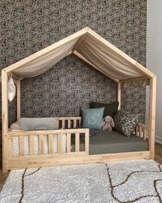 a wooden bed with a canopy over it and pillows on the floor next to it